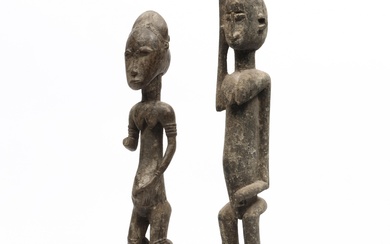 An African standing female figure with one arm missing and a wooden figure with one raised arm.