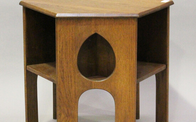 An early 20th century Arts and Crafts oak hexagonal book table, three sides pierced with teardrop mo