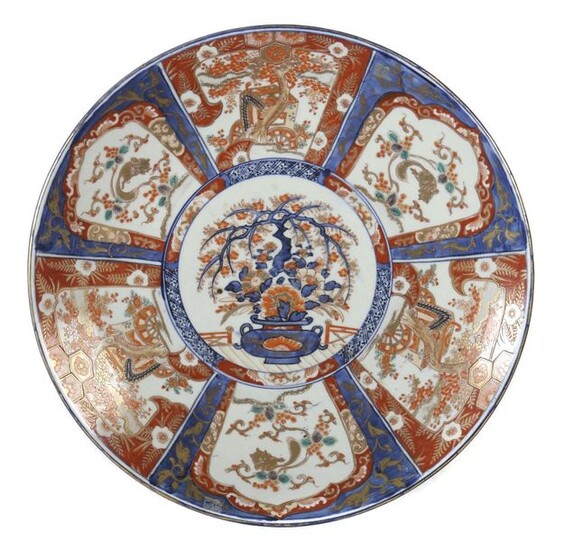 Big plate with Imari decor Japan, 20th century, porcelain, underglazed blue and onglazed red decor in cartouches framed with representations like vases, ornamental trees and rodents, decorated with ornamental gold, d: 46 cm. Burn mark, chip.