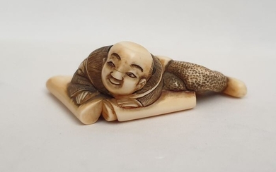 Netsuke - Ivory - carved as boy lying on two open scrolls - Japan - Late 19th century (Meiji period)