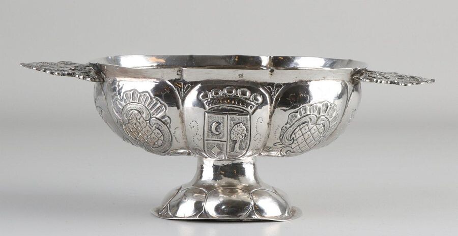 Silver brandy bowl, 833/000, oval lobed model decorated with driven family coat of arms, placed on an oval base and provided with handles of 2 standing lions wearing a crown. MT .: R. Huishuizen, Groningen, last year: K: 1819.24x12x9cm ca 193 grams...