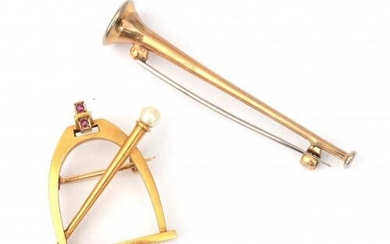 Two gold brooches in het shape of a stirrup and a trumpet. The 14 karat gold stirrup is from the late nineteenth century, featuring two rubies and a pearl. The trumpet was found below the Dutch legal gold grade of 14 karat gold. Gross weight: 8 g.
