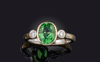 Une bague en grenat tsavorite et diamant, le grenat vert ovale flanqué de diamants ronds...