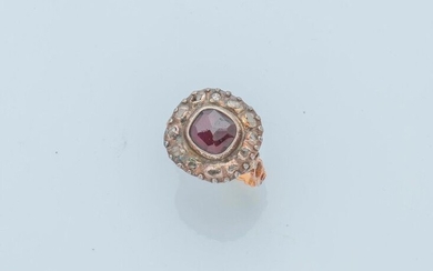 18 karat yellow gold (750 thousandths) and silver (800 thousandths) ring set with a faceted garnet in a closed setting, surrounded by rose-cut diamonds. The setting dressed with acanthus leaves.