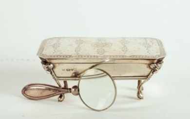 A silver dressing table box with hinged cover and ram