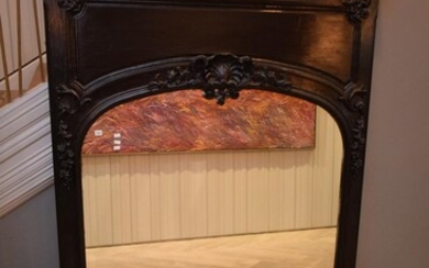 A HEAVILY DETAILED BLACK PAINTED OVER MANTLE MIRROR (180H X 132W CM)