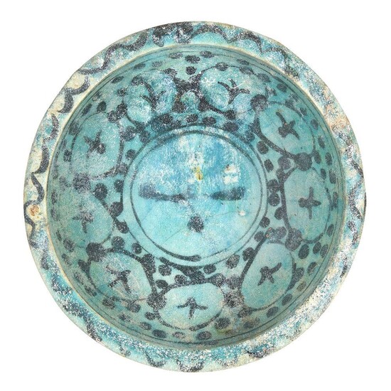 A Kashan turquoise-glazed pottery bowl, Iran, 12th century, underglaze painted in black with a series of circles containing abstract motifs to centre well, o a ground of black dots, 22cm diameter Provenance: Private collection London since 1968