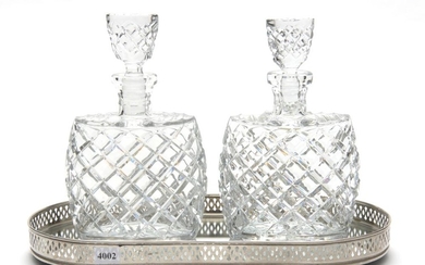 A PAIR OF 1960S HEAVY CUT CRYSTAL DECANTERS ON PIERCED PLATED TRAY, EACH DECANTER 24 CM HIGH, THE TRAY 37.5 CM WIDE
