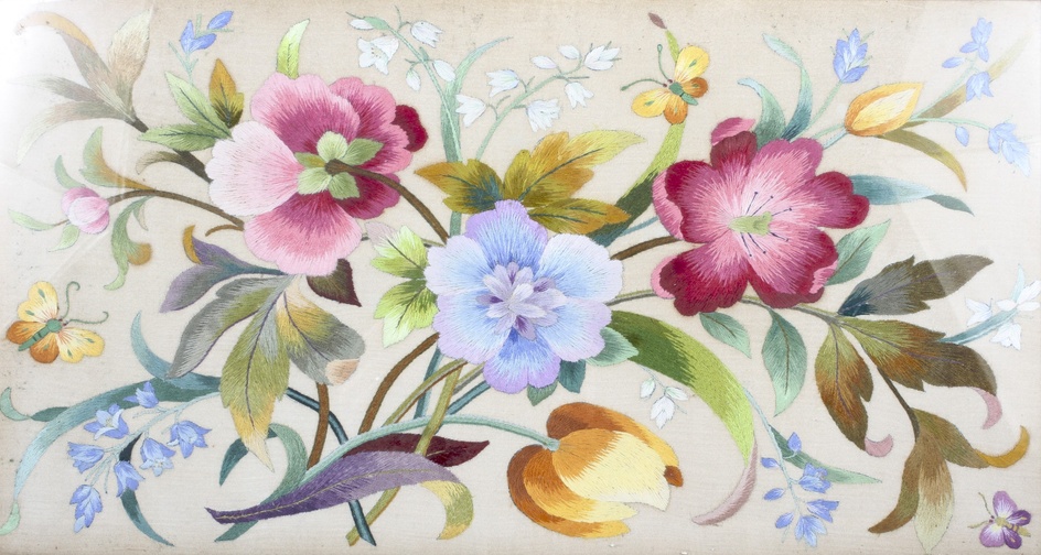 A framed early-mid 20th century silk needlework embroidered panel. Worked with a loose bouquet of flowers in coloured silk threads on an ivory coloured ground, 33cm x 59cm overall