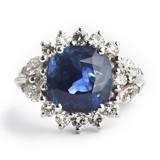 A sapphire and diamond ring set with a cushion-cut sapphire weighing app. 7.70 ct. encircled by diamonds, mounted in 18k white gold. G-H/VVS-VS.