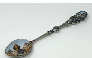 A silver coloured metal and enamel spoon, decorated ancient ...