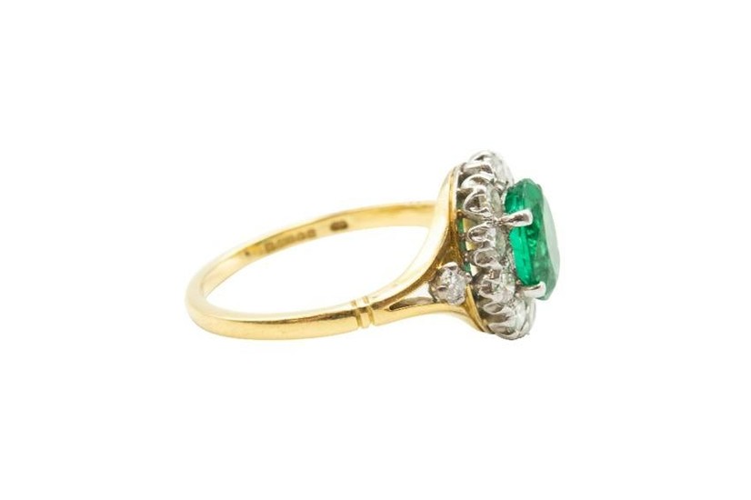 AN EMERALD AND DIAMOND CLUSTER RING Centrally-set with