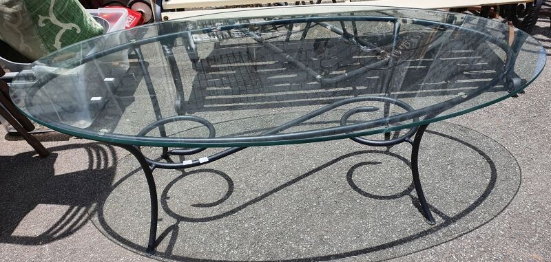 AN OVAL GLASS TOP WROUGHT IRON BASED COFFEE TABLE