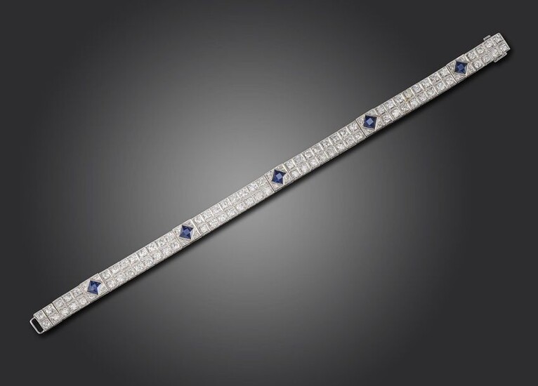 An Art Deco sapphire and diamond bracelet, set with pairs of old circular-cut diamonds millegrain set in square collets, separated with five French-cut sapphires, in platinum, 18cm long, case