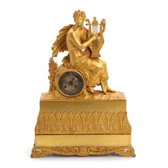 An early 19th century French gilt bronze mantle clock, decorated with a young man in classical robe, silvered dial with black Roman numerals. H. 51 cm.