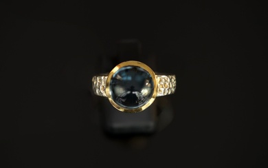BAGUE en argent doré et argent 925/°° centrée d'un cabochon rond de topaze bleue, l'anneau...