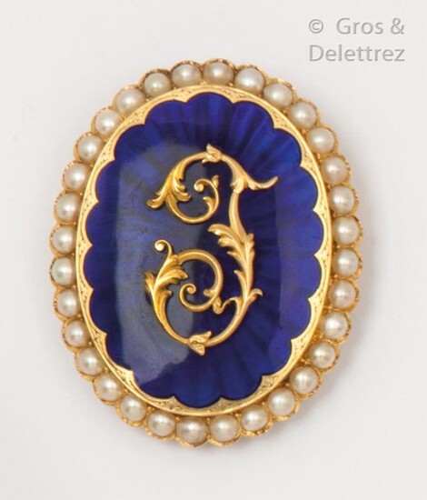 Brooch in blue enamelled yellow gold, set with the letter "T" in gold in a circle of half pearls. Dimensions: 4 x 5cm. Gross weight: 19.2g. With case.