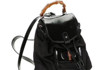 Gucci: A “Bamboo Backpack” made of black fabric with black patent details, bamboo handle and button, small pocket on the front and one compartment.