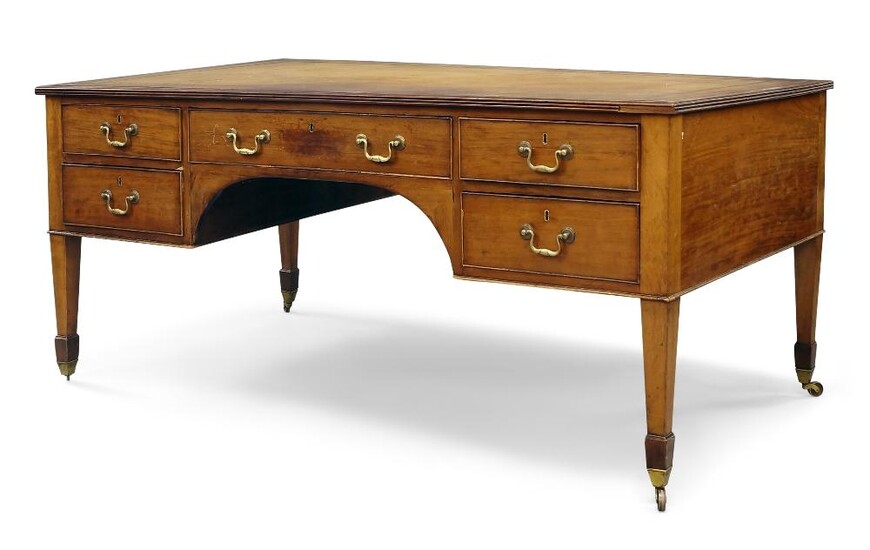 The Editor's Desk A George III style mahogany desk, early 20th century, with leather inset top over a knee hole frieze arranged with five drawers and opposed by dummy drawers, standing upon square tapering legs, with spade feet and brass casters...