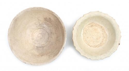 Two early white glazed Chinese ceramic bowls. The first with a modelled high relief of phoenix. The second a shallow bowl with a scalloped rim. Presumably Song dynasty.