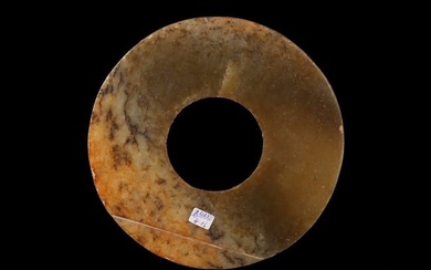A CHINESE ARCHAIC GREEN AND RUSSET JADE DISC BI
