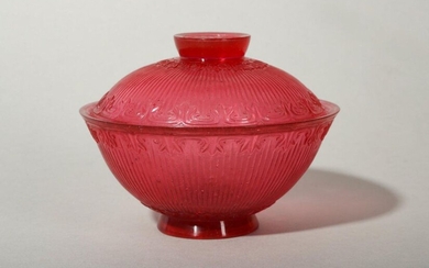 A CHINESE PEKING GLASS RUBY RED TEA BOWL AND COVER. Qing Dynasty, Jiaqing mark and of the period. With rounded sides rising from a slightly tapered foot to a flaring rim, decorated with vertical ribbing within a band of foliage below the rim and above...