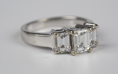 An 18ct white gold and diamond three stone ring, claw set with a row of three emerald cut diamonds