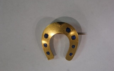 Brooch in 18 kt yellow gold affecting the shape of a horseshoe and adorned with sapphires. Gross weight 6,61g . Length 3 cm .
