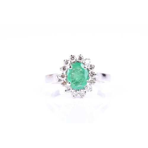 An emerald and diamond cluster ring, the oval cut emerald, i...