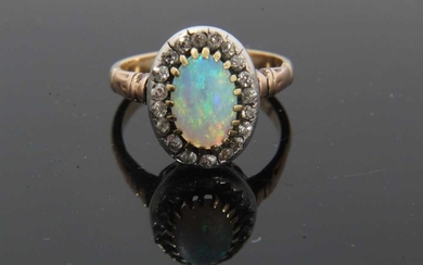 Antique opal and diamond cluster ring with an oval cabochon opal surrounded by nineteen old cut diamonds in silver collet setting with pierced gold gallery on gold shank
