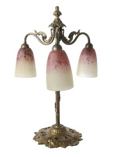 Art Nouveau table lamp France, Épinay-sur-Seine, Verrerie Schneider, early 20th century, glass/brass, brass frame in relief with an open-worked base, the shaft fluted, surrounded by a floral vine, three flames, the lampshades attached to three curved...