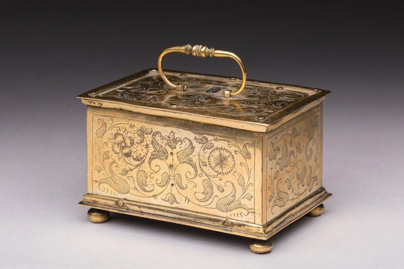 GOLDEN METAL BOX engraved with chiselled decoration of interlacing, foliage and floral motifs on all sides and visible screws, the upper part with movable handle. The interior reveals a complication mechanism. Four ball feet. Work in the tradition of...