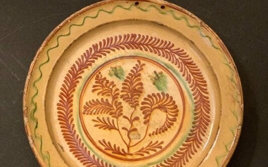 Large dish decorated with circumscribed ferns and a wave on the rim in pinkish earth with red and green barolet glaze on a white background that has turned yellow under the lead glaze. Probably Savoy, early 20th century.