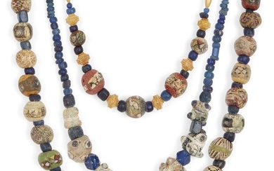 Two mostly Roman mosaic glass bead necklaces and an eye bead necklace 1st Century B.C.-A.D. and Later A necklace including five Roman spherical face beads, interspersed with blue glass beads and later gold spacer beads; another necklace with some...