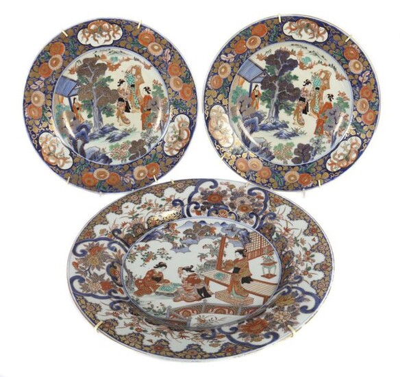 3 Imari wall plates Japan/China, 1st half of the 20th century, porcelain, 1 pair of plates with figural decor of entertaining ladies in the garden in the plate mirror, framed by phoenix and flower decor as well as 1 plate with depiction of...