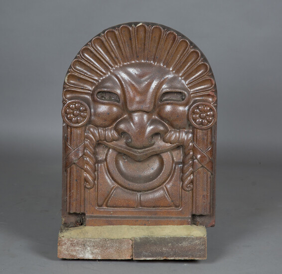 A 19th century salt glazed stoneware arched tablet, moulded as a grotesque mask, height 61cm, width