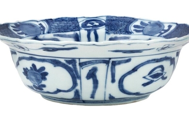 A Chinese blue and white 'Kraak' foliate rim bowl, Wanli period, standing on a short foot rising to deep rounded sides to flared foliate rim, painted to the central roundel with rocks and chrysanthemum, the exterior painted with alternating panels...