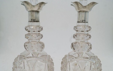 A pair of cut glass decanters and stoppers with silver collars, Sheffield, 1924, probably Walker & Hall, marks rubbed, the necks with faceted graduating rings above faceted and star cut bodies, 29cm high (2)
