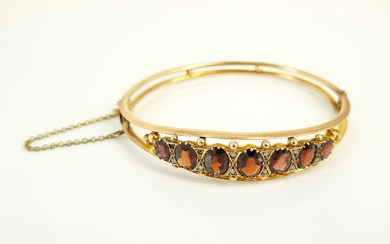 AN ANTIQUE SIX-STONE GARNET AND 9ct ROSE GOLD BANGLE; Chester 1911