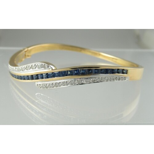 An 18ct gold sapphire and diamond half hinged bangle. Appro...