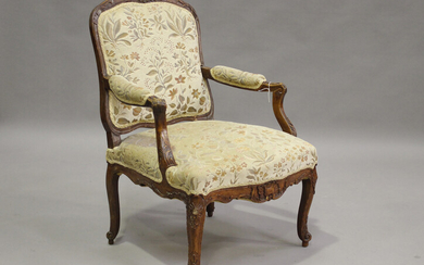 An 18th century French provincial walnut fauteuil armchair, the showframe carved with foliage and ac