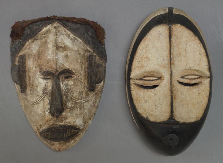 An Igbo mask, Nigeria, second half 20th Century, with applied white pigment and carved stylised features, 31cm high together with another African mask, 31cm high (2)