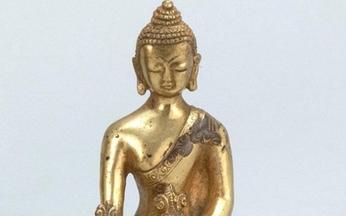CHINESE GILT-BRONZE FIGURE OF BUDDHA Seated in earth touching posture and holding a censer and a flower blossom. Height 4.2".