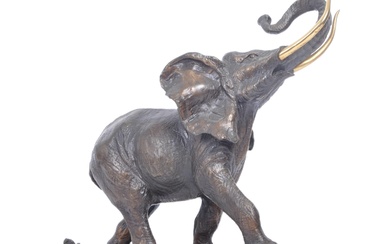 A 20th century patinated bronze elephant being set with gilt brass tusks and raised over a naturalistic plinth base. The base monogrammed FM. Measures 23cm high.