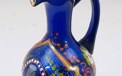 A Bohemian blue glass jug, 19th century, the body enamelled and gilded with foliate motifs and cartouches, featuring an oval portrait of Mozaffar ad-Din, Shah of Qajar, 22.5cm high