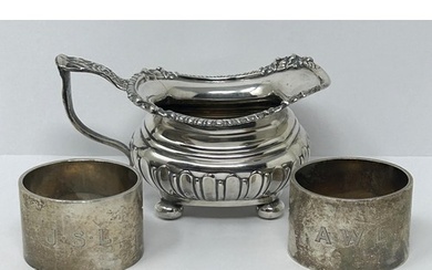 A George V silver cream jug, and two silver napkin rings, va...