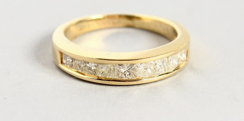 A YELLOW GOLD PRINCESS CUT DIAMOND HALF ETERNITY RING.