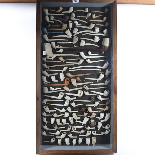 A framed display of Antique clay pipes, including figural ex...