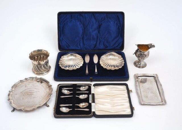 A group of silver comprising: a cased set of two silver butter dishes with knives, Sheffield, 1908, Atkin Bros, both designed as scallop shells; a Mappin & Webb silver card tray, Sheffield, 1979, with presentation engraving, 15.7cm dia.; a small...