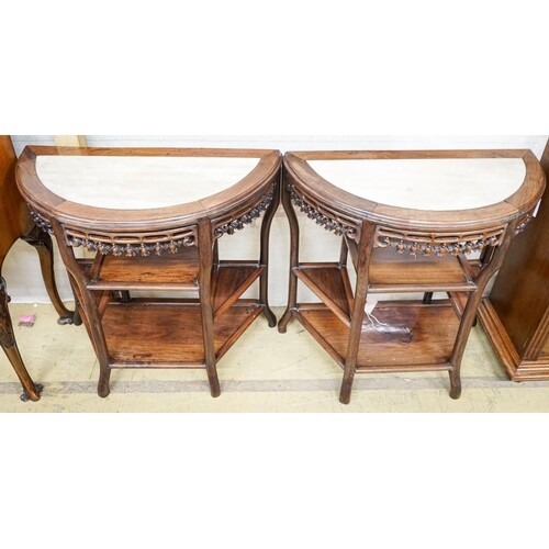 A pair of Chinese marble-topped demi lune console tables, wi...